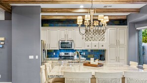 A modern kitchen with white cabinets, a granite island, and a chandelier. - Snowbird-Friendly Home with Private Pool, Grill, AC, Fireplace, & WiFi - Dogs OK (Glendale)