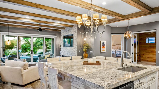 A modern kitchen with a large island, built-in appliances, and a dining area with a sofa and chairs. - Snowbird-Friendly Home with Private Pool, Grill, AC, Fireplace, & WiFi - Dogs OK (Glendale)