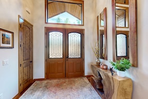A wooden door with a glass panel, a large mirror, and a potted plant on a wooden console. - Luxurious mountain home w/ firepit & grill - close to hiking, fishing, & golf (Show Low)