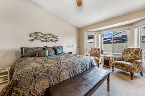 A bedroom with a large bed, a bench, a chair, and a wall-mounted decoration. - Lovely getaway with private pool, putting green & desk (Gilbert)