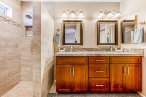 A modern bathroom with a walk-in shower, double vanity with a granite countertop, and wooden cabinets. - Lovely getaway with private pool, putting green & desk (Gilbert)