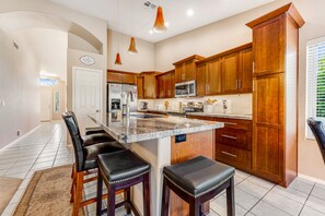 A kitchen with wooden cabinets, a granite countertop, and a built-in island with bar stools. - Lovely getaway with private pool, putting green & desk (Gilbert)