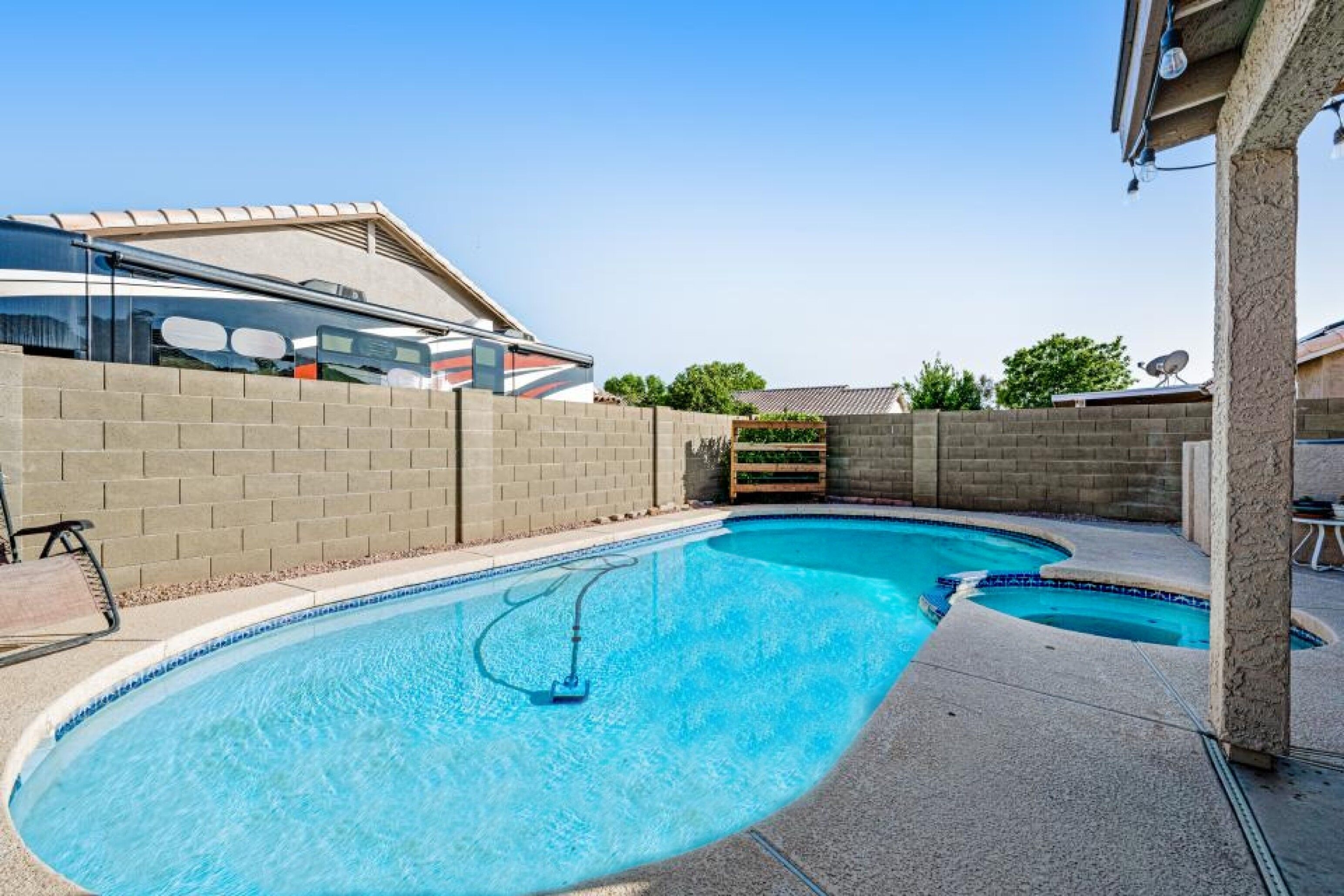 A swimming pool with a built-in slide, surrounded by a brick wall and a wooden deck.