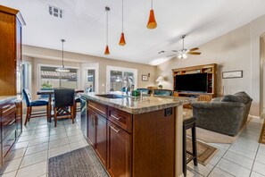 Une cuisine spacieuse dotée d’un grand îlot central, de meubles en bois et de luminaires suspendus.