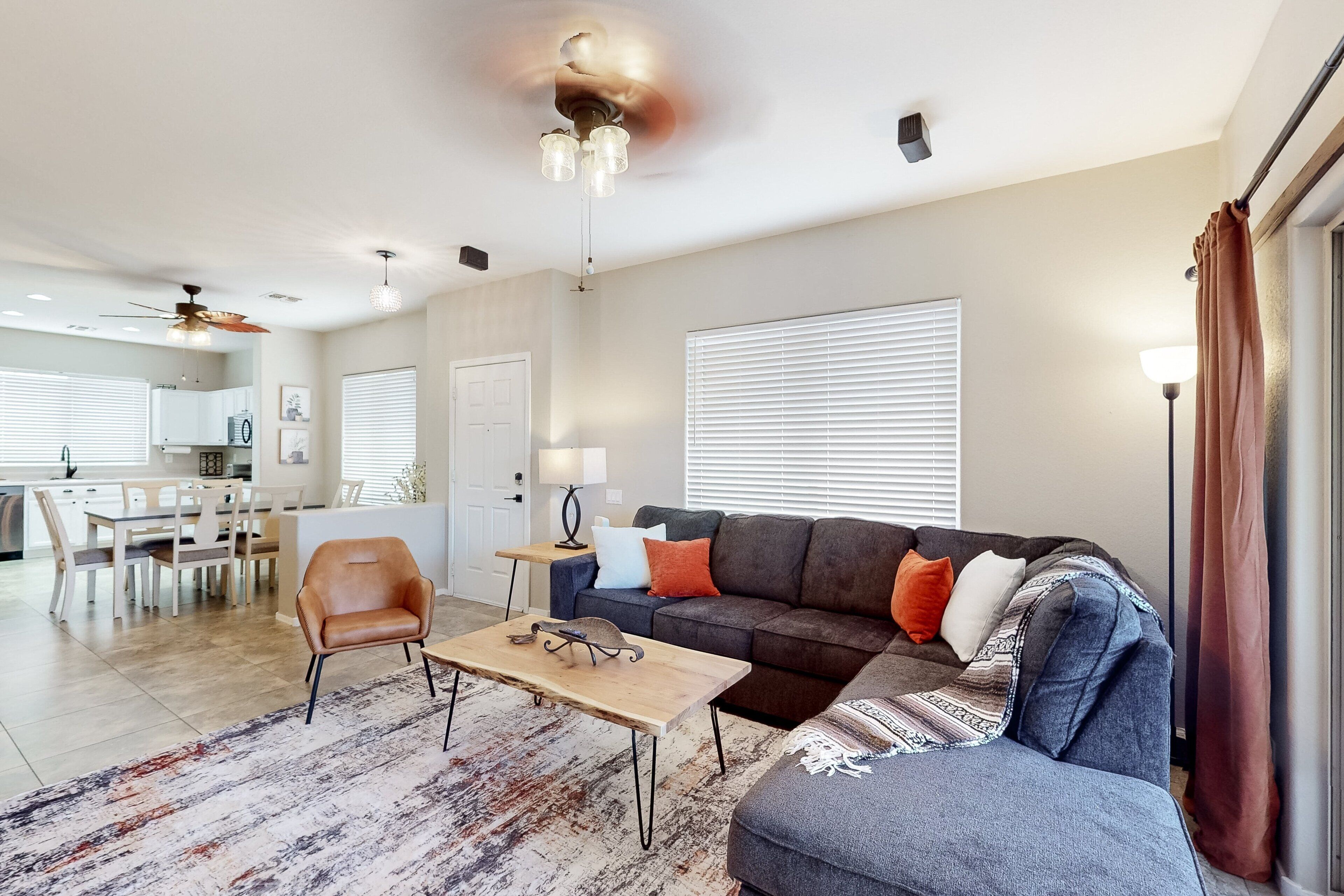 Una sala de estar moderna con un sofá, un sillón, una mesa de centro y un área de comedor al fondo.