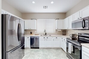 A modern kitchen with white cabinets, stainless steel appliances, and a central island. - Dog-friendly home with private heated pool, enclosed backyard, patio, grill, W/D (Gold Canyon)