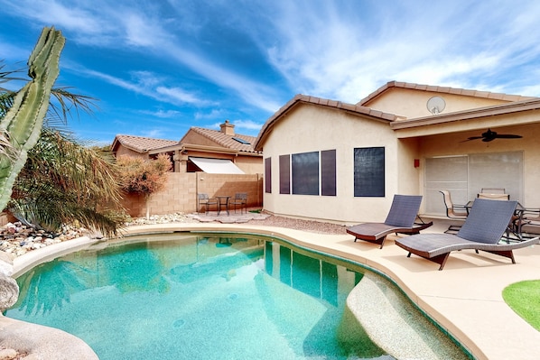 Un espace aménagé au bord de la piscine, comprenant une maison, une piscine et des chaises longues.