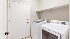 A laundry room with a white door, a washing machine, and a dryer.