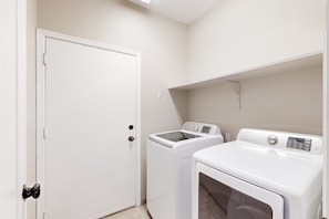 Une buanderie avec une porte blanche, un lave-linge et un sèche-linge.