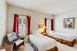 A room with two single beds, a wicker chair, a small table with a lamp, and a painting on the wall. - Comfortable getaway with hot tub, pool, private BBQ & full kitchen (Oro Valley)