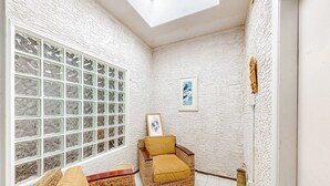 A corner room with a large window, wicker furniture, and a framed picture on the wall. - Lake view desert stay with pool, patio, grill, & smart TVs - snowbird-friendly (Gilbert)