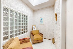 A corner room with a large window, wicker furniture, and a framed picture on the wall.