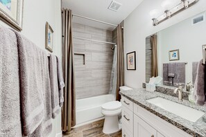 A modern bathroom with a bathtub, toilet, and vanity with a sink. - Lake view desert stay with pool, patio, grill, & smart TVs - snowbird-friendly (Gilbert)