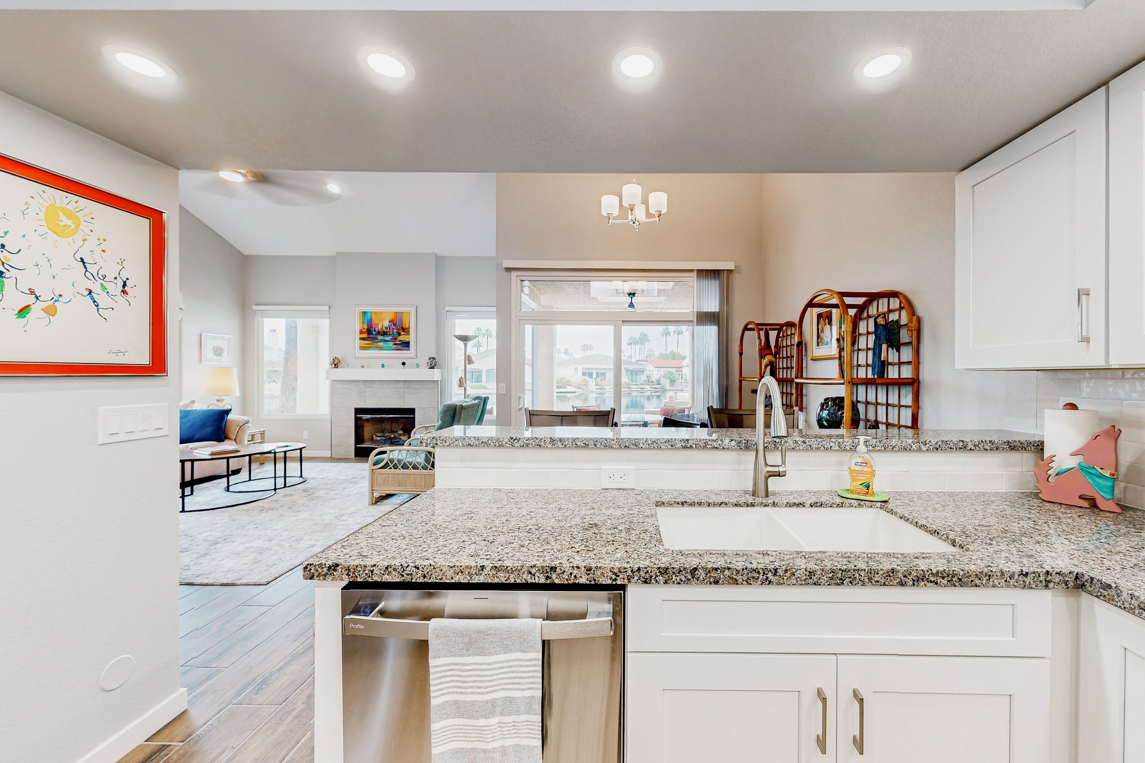 A modern kitchen with granite countertops, stainless steel appliances, and a view to the living area.