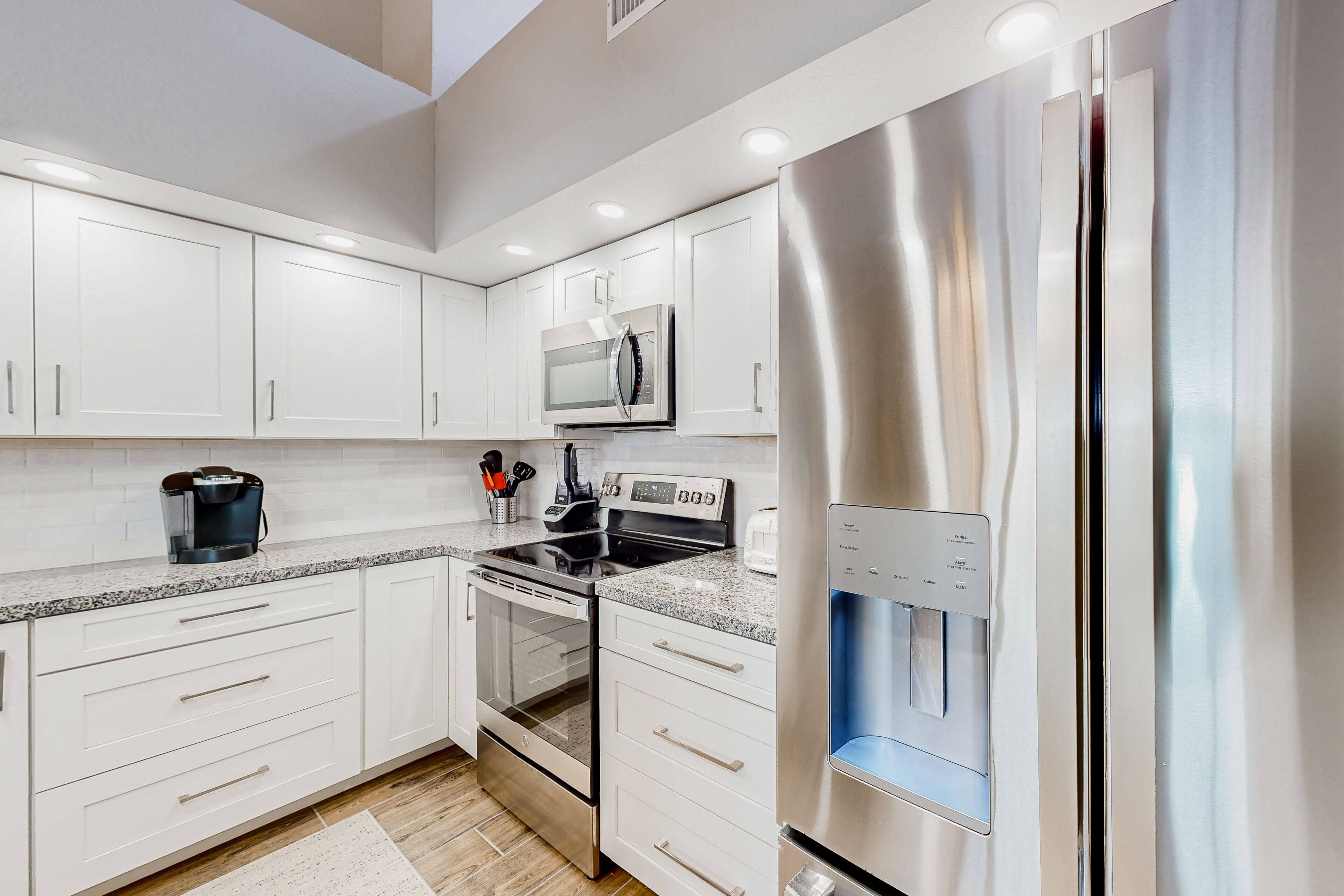 A modern kitchen with white cabinets, stainless steel appliances, and a built-in water dispenser.