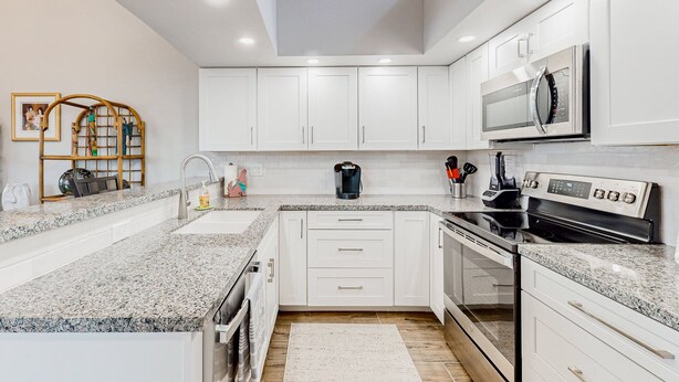 A modern kitchen with white cabinets, granite countertops, a built-in oven, and a microwave. - Lake view desert stay with pool, patio, grill, & smart TVs - snowbird-friendly (Gilbert)