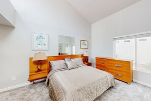 A bedroom with a large bed, wooden nightstands, a dresser, and a window with a view. - Lake view desert stay with pool, patio, grill, & smart TVs - snowbird-friendly (Gilbert)