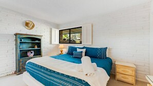 Une chambre à coucher avec un lit, une table de chevet, une commode et une fenêtre avec des volets.