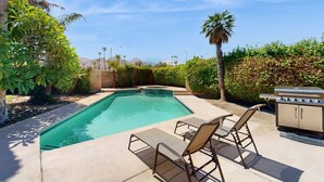 A swimming pool with lounge chairs and a barbecue grill. - Beautiful home with private pool, enclosed backyard & mountain view (Indian Wells)