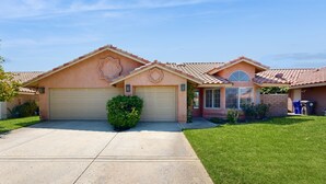 A two-story house with a garage, a front yard, and a well-maintained lawn. - Beautiful home with private pool, enclosed backyard & mountain view (Indian Wells)