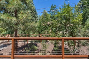 A wooden fence with a metal railing, a clear sky, and dense green foliage in the background. - Dog-friendly forested home with wraparound deck, pool table (Pinetop)