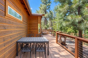 A wooden cabin with a deck, outdoor seating, and a view of pine trees. - Dog-friendly forested home with wraparound deck, pool table (Pinetop)