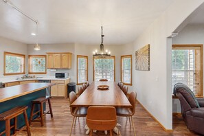 A spacious kitchen with a long dining table, wooden cabinets, and a built-in microwave. - Dog-friendly forested home with wraparound deck, pool table (Pinetop)