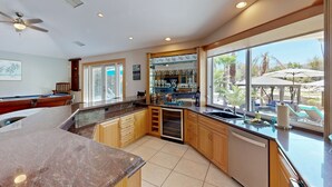 Una cocina moderna con una isla grande, armarios de madera y vistas al exterior.