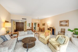 A living room with a sofa set, a coffee table, and a chair. There is a dining area with a table and chairs in the background. - Inviting townhouse with pool, enclosed yard, patio, mountain view & W/D (Tucson)