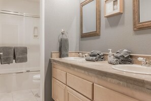 A bathroom with two sinks, a mirror, and a shower area. - Mountain view home with pool, spa and dog friendly (La Quinta)