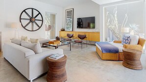 Ein modernes Wohnzimmer mit Sofa, Sesseln, Couchtisch und Fernseher.