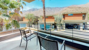 Ein Balkon mit zwei Stühlen, einem Pool und einem Gebäude mit Wüstenlandschaft im Hintergrund.
