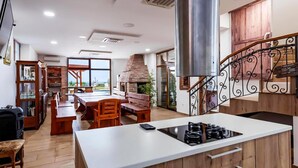 A modern kitchen with a central island, a built-in oven, and a staircase with decorative railings.
