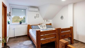 A bedroom with a wooden bed, a window with blinds, a radiator, and a small wall decoration.