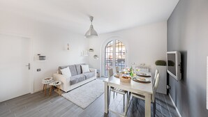 Una sala de estar moderna con un sofá gris, una mesa de comedor con comida y un televisor montado en la pared.