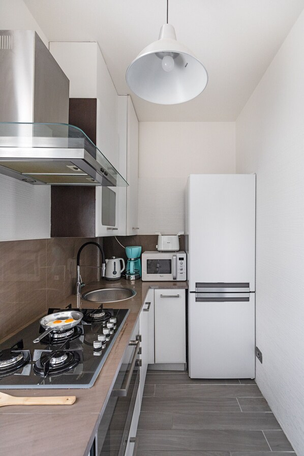 A modern kitchen with a gas stove, a microwave, a toaster, and a refrigerator.