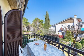 Ein Balkon mit Tisch für zwei Personen, einer Weinflasche und einem Teller Essen.