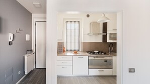 Una cocina moderna con armarios blancos, electrodomésticos de acero inoxidable y un ventanal con cortinas.