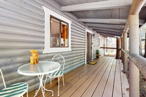 Eine überdachte Veranda mit Tisch und Stühlen, einem Fenster und einer Tür.