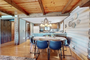 A log cabin interior with a dining area, kitchen, and a large window. - Modern lakefront cabin with bbq, gas fireplace, amazing views (Munds Park)