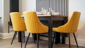 A dining area with a wooden table, four yellow chairs, and a black floor lamp. - Modern 2 En-Suite Bedrooms Worcester, Free Parking (Worcestershire)