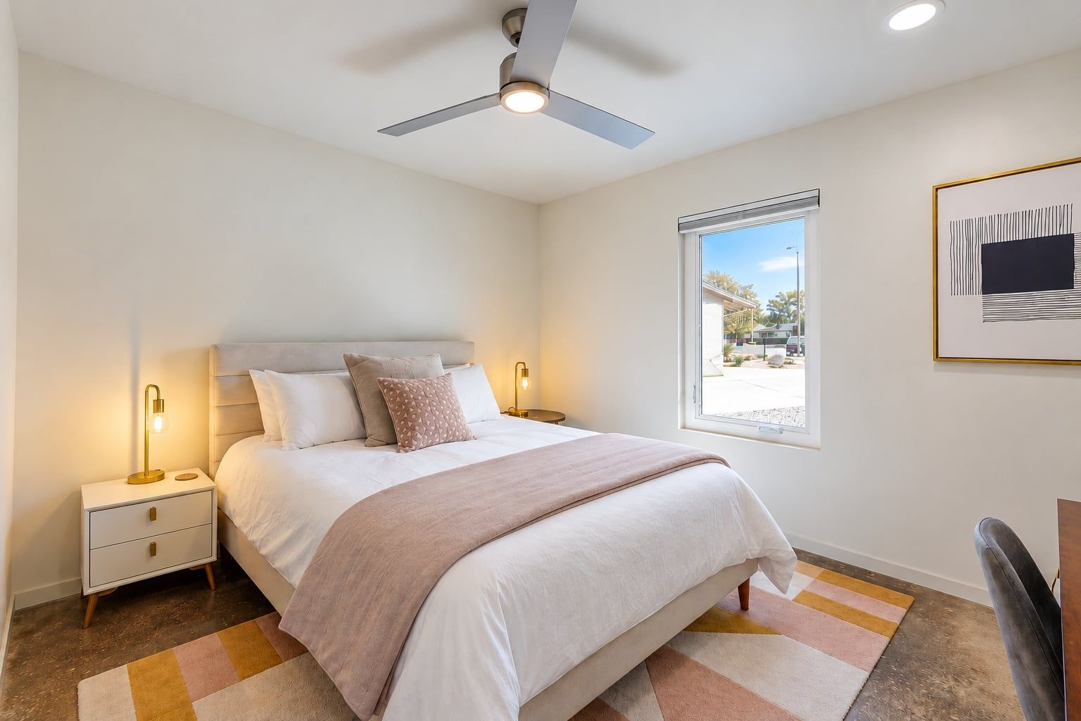 A bedroom with a bed, bedside tables, a ceiling fan, a window, and a framed picture on the wall.