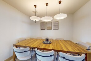Une salle de conférence avec une table en bois, six chaises et trois lampes suspendues.