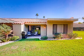A two-story house with a patio, outdoor seating, and a small garden. - Resort living golf getaway with country club, near Joshua Tree National Park (Palm Desert)