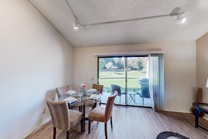 A dining area with a glass table and chairs, a view of a golf course through a sliding glass door, and a ceiling with recessed lighting. - Resort living golf getaway with country club, near Joshua Tree National Park (Palm Desert)