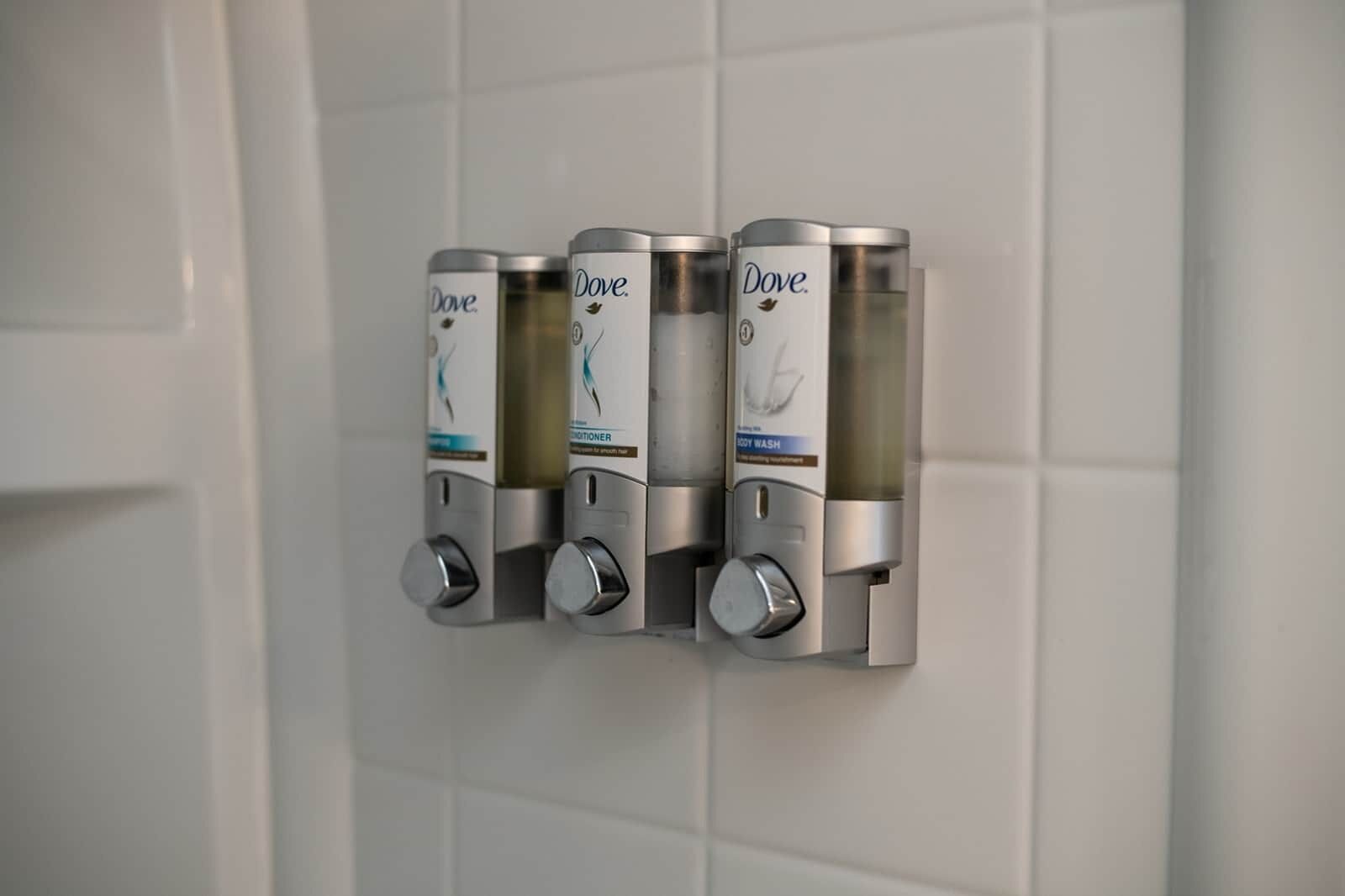 A wall-mounted dispenser with Dove soap and lotion.