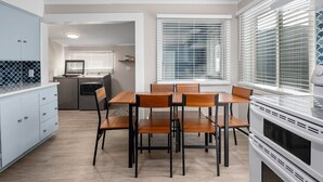 A modern kitchen with a dining area, white cabinetry, and a built-in oven. - Salty Dog Beach House close to beach - Dog Friendly! (Pacific Beach)