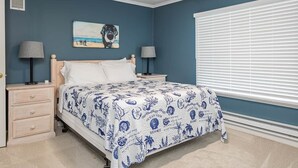 A bedroom with a bed, two bedside tables, a nightstand, a painting, and a window with blinds. - Salty Dog Beach House close to beach - Dog Friendly! (Pacific Beach)