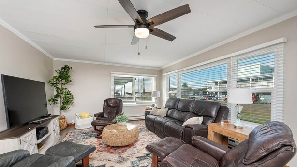 A living room with a flat-screen TV, leather sofas, a coffee table, and a ceiling fan. - Salty Dog Beach House close to beach - Dog Friendly! (Pacific Beach)
