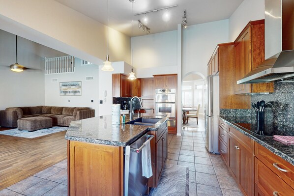Una cocina amplia con armarios de madera, encimera de granito y electrodomésticos de acero inoxidable.